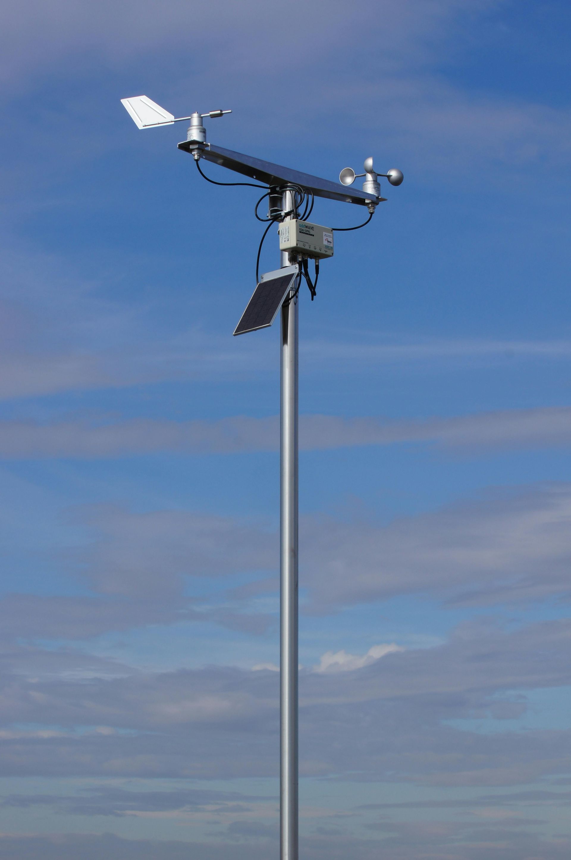 Weather station on a tall pole against a blue sky