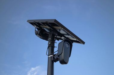 Solar streetlight with attached device mounted on a pole against a blue sky