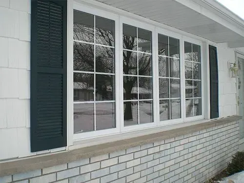 A white house with black shutters and a large window
