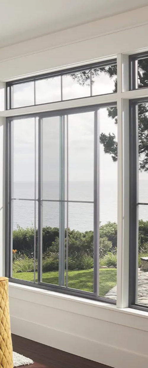 A living room with a lot of windows and a view of the ocean.