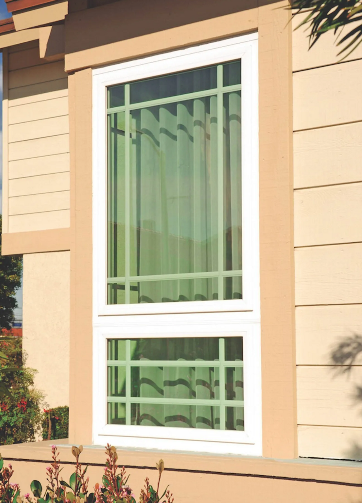 A window on the side of a house with green curtains