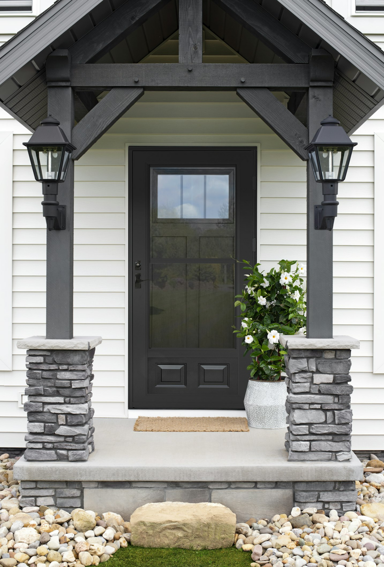 A white house with a black door and a stone porch.