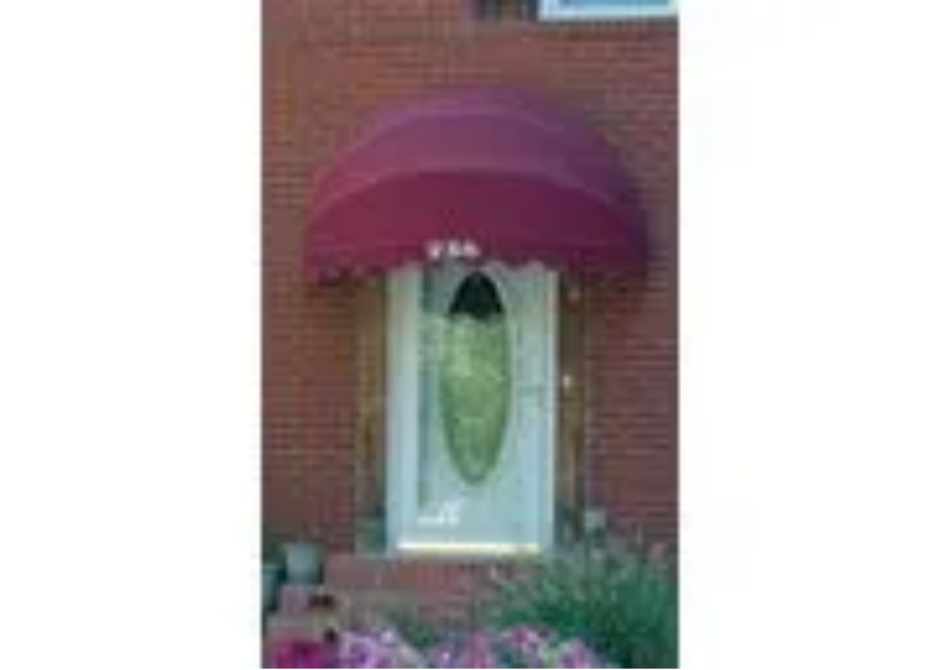A white door with a red awning over it.