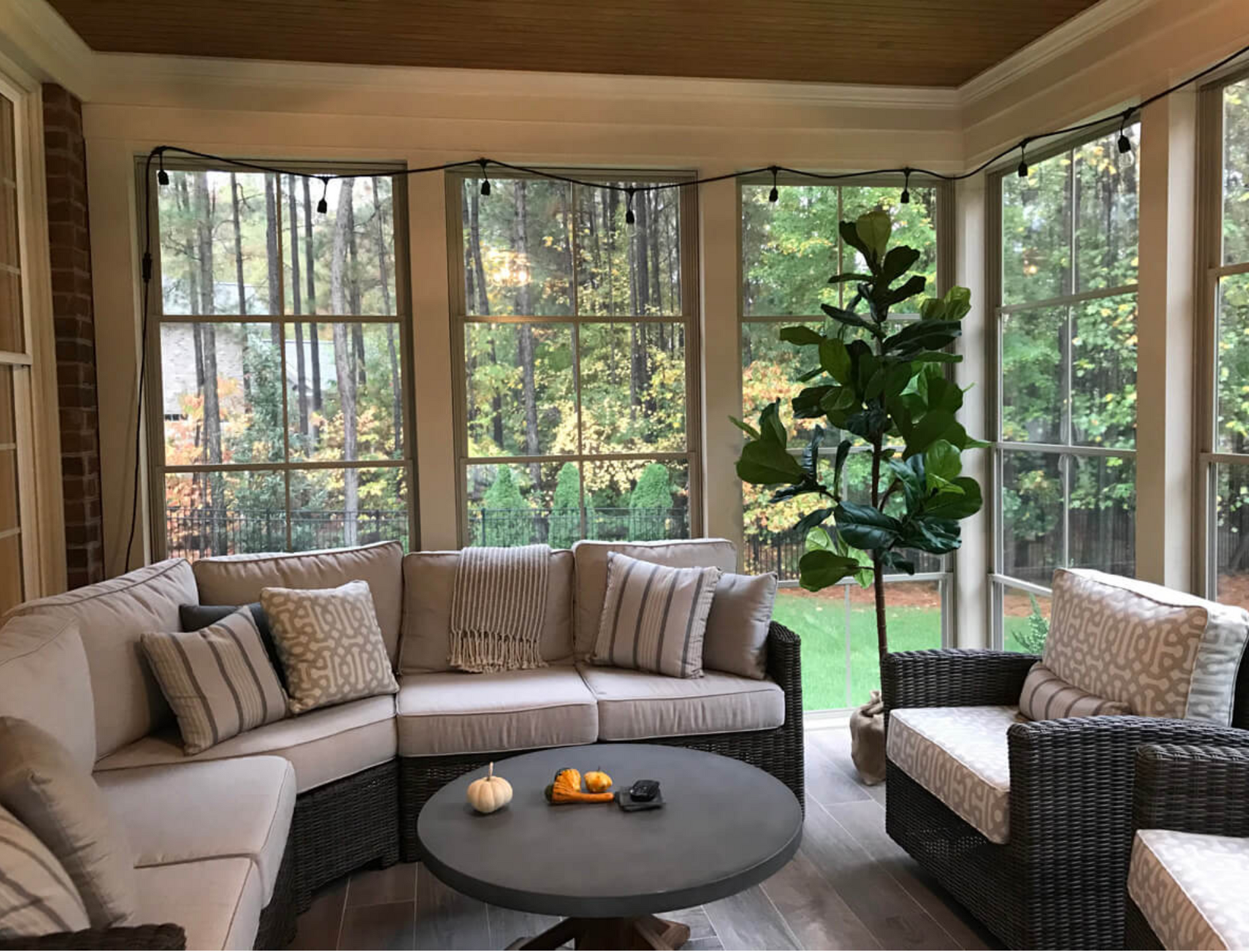 A screened in porch with a couch , chairs , and a table.
