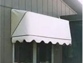 A white awning is hanging over a window on the side of a building.