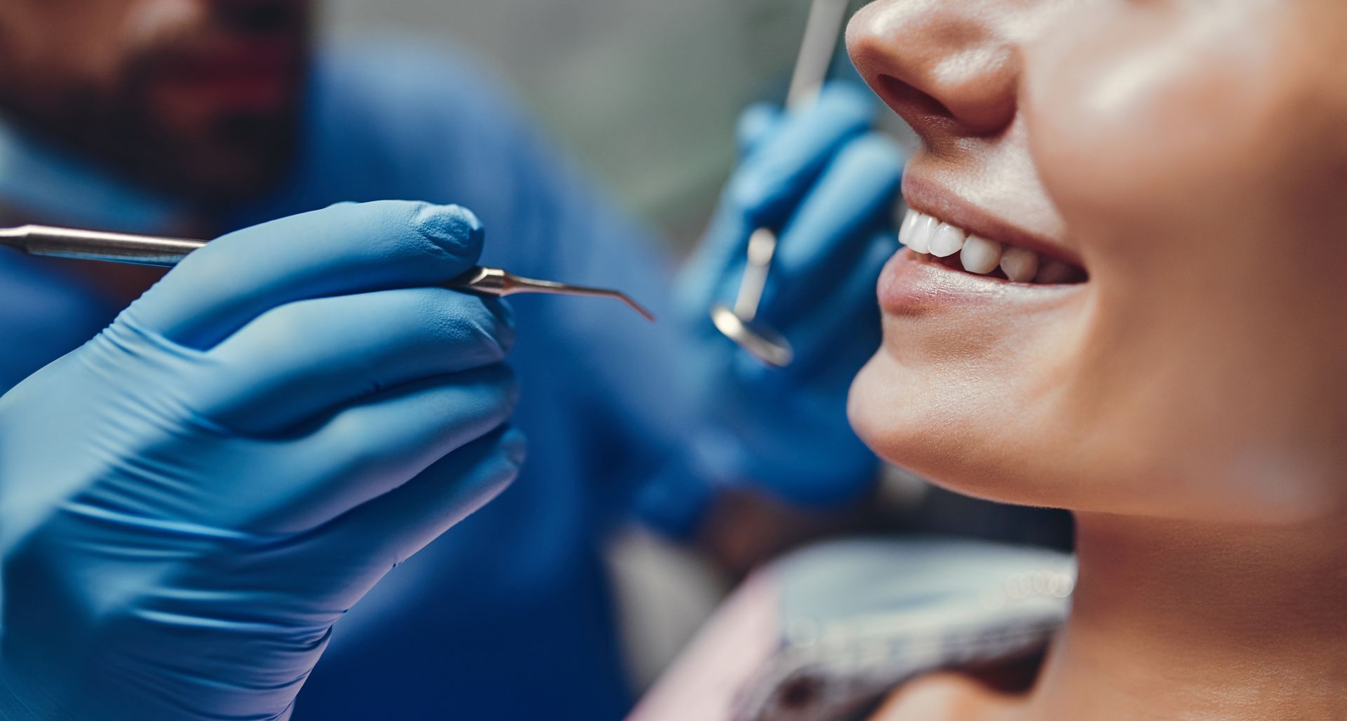 Dentist using tools on a patient’s mouth during a dental procedure.