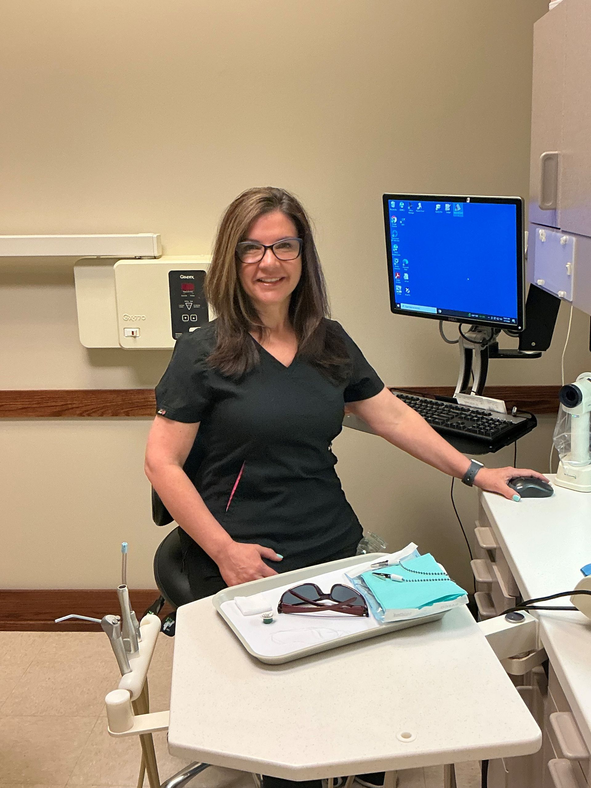 Woman standing beside a medical exam table in a clinic, next to a computer monitor. Woman standing beside a medical exam table in a clinic, next to a computer monitor.