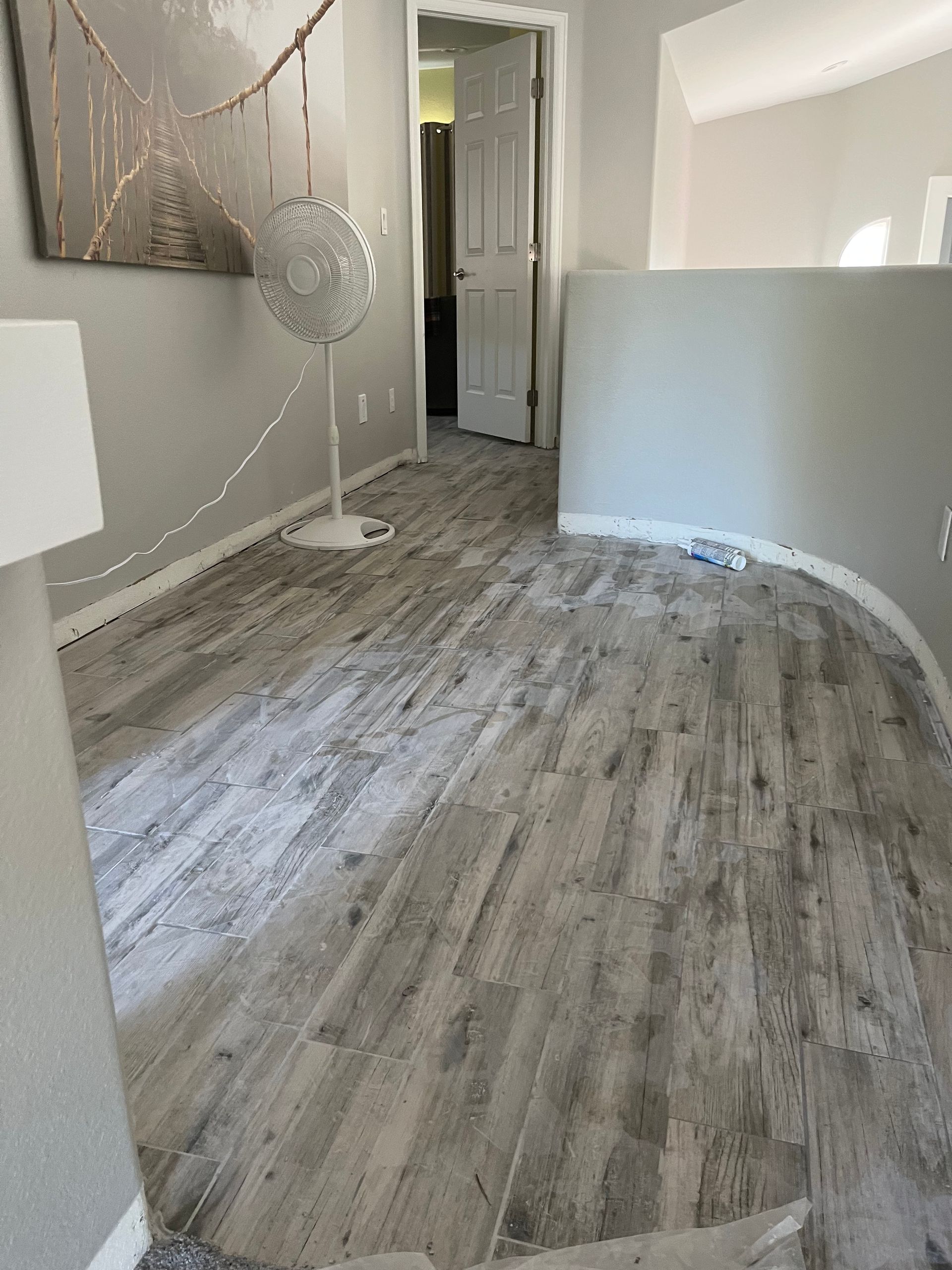 Empty room with gray wood-look flooring, white walls, and a doorway in the back.