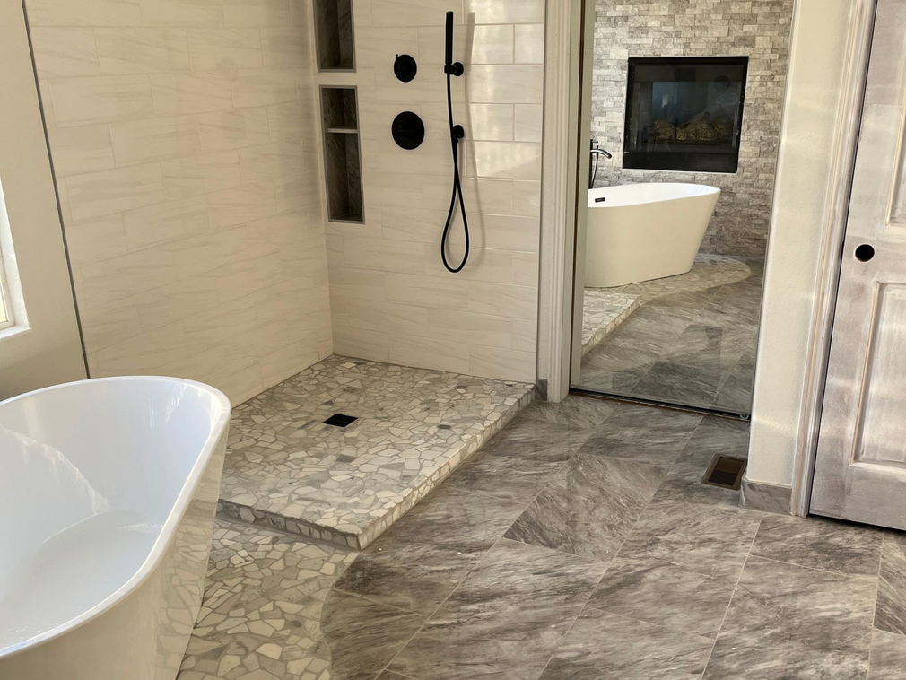 Modern bathroom with freestanding tub, walk-in shower, stone tile, and a wall-mounted toilet
