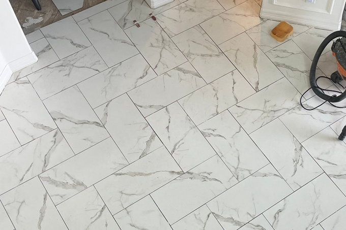 White marble-patterned tile floor with a visible vacuum cleaner and a small wooden object near a doorway