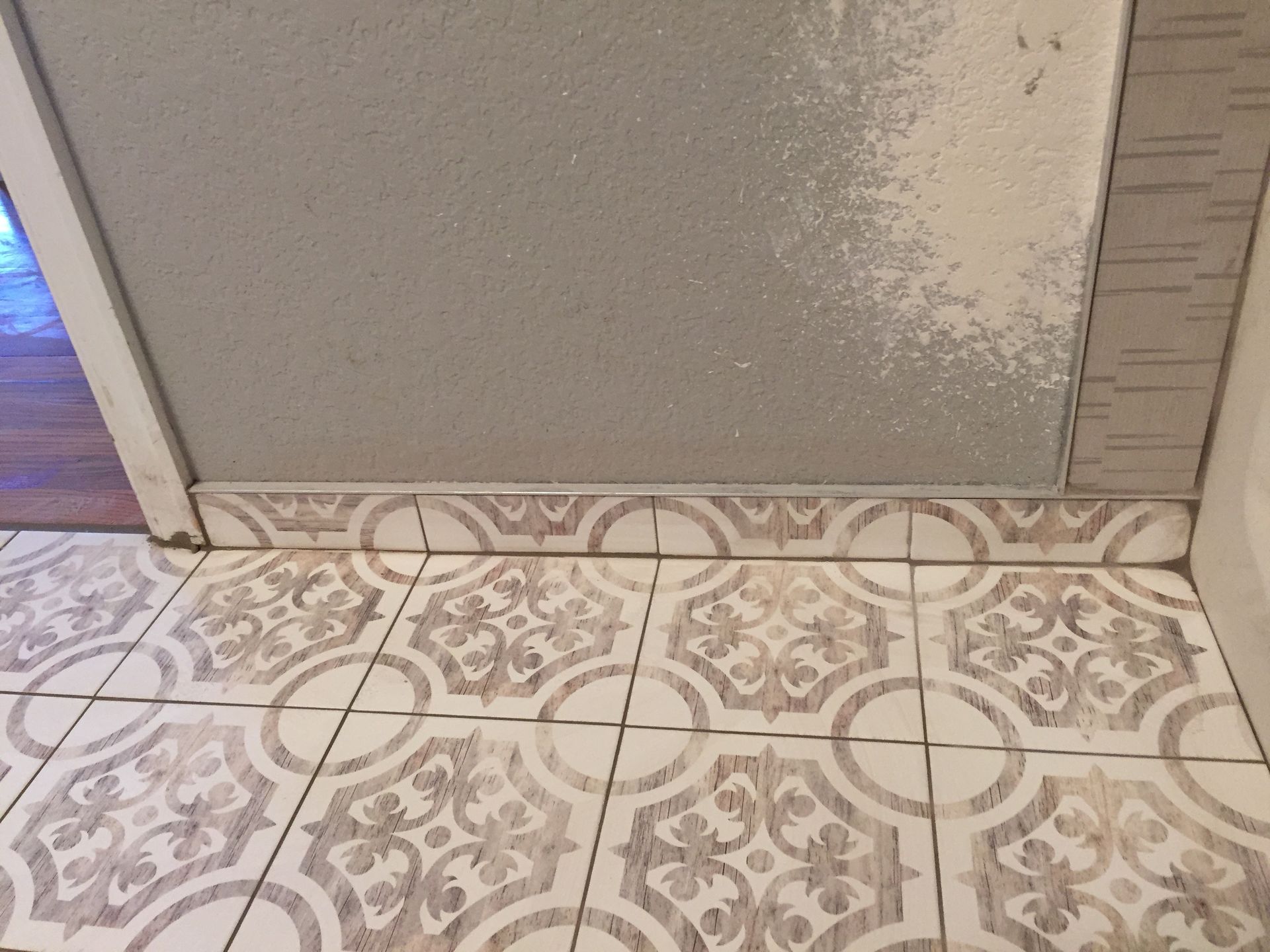 Tiled floor meeting frosted glass door with a blue-lit room visible at left edge