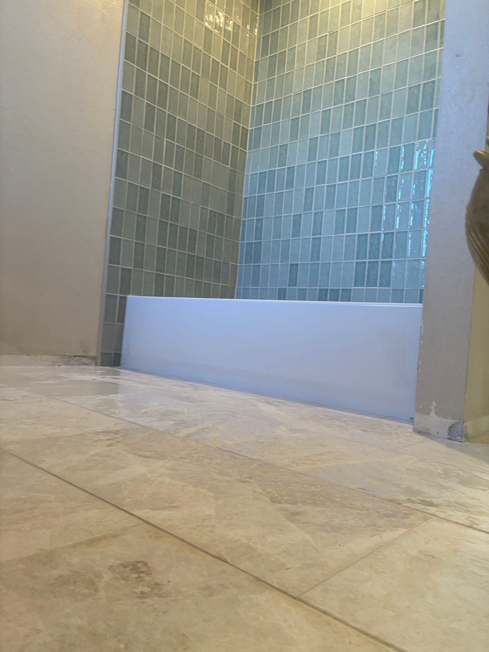 Modern bathroom shower with blue-green tiled wall and beige floor tiles