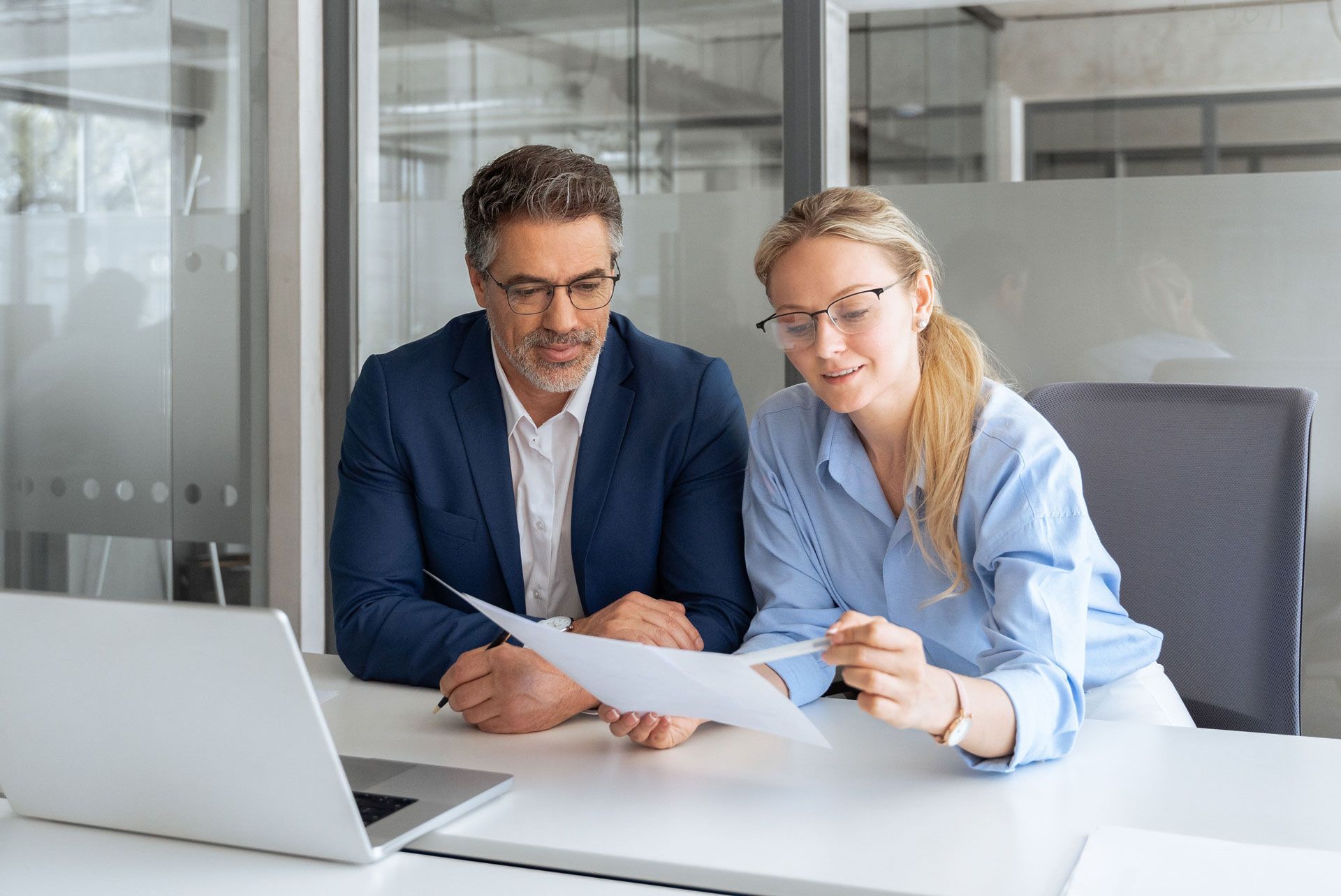 A man and a woman are sitting at a table looking at a piece of paper.