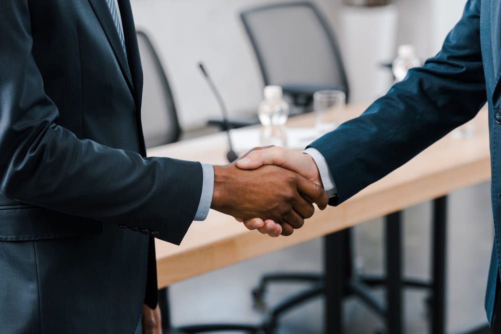 Two businessmen are shaking hands in a conference room.