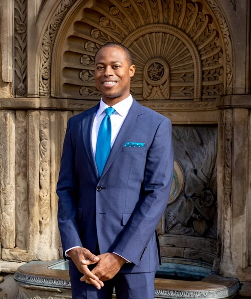A man in a suit and tie is standing in front of a building.