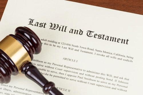 A wooden gavel is sitting on top of a last will and testament