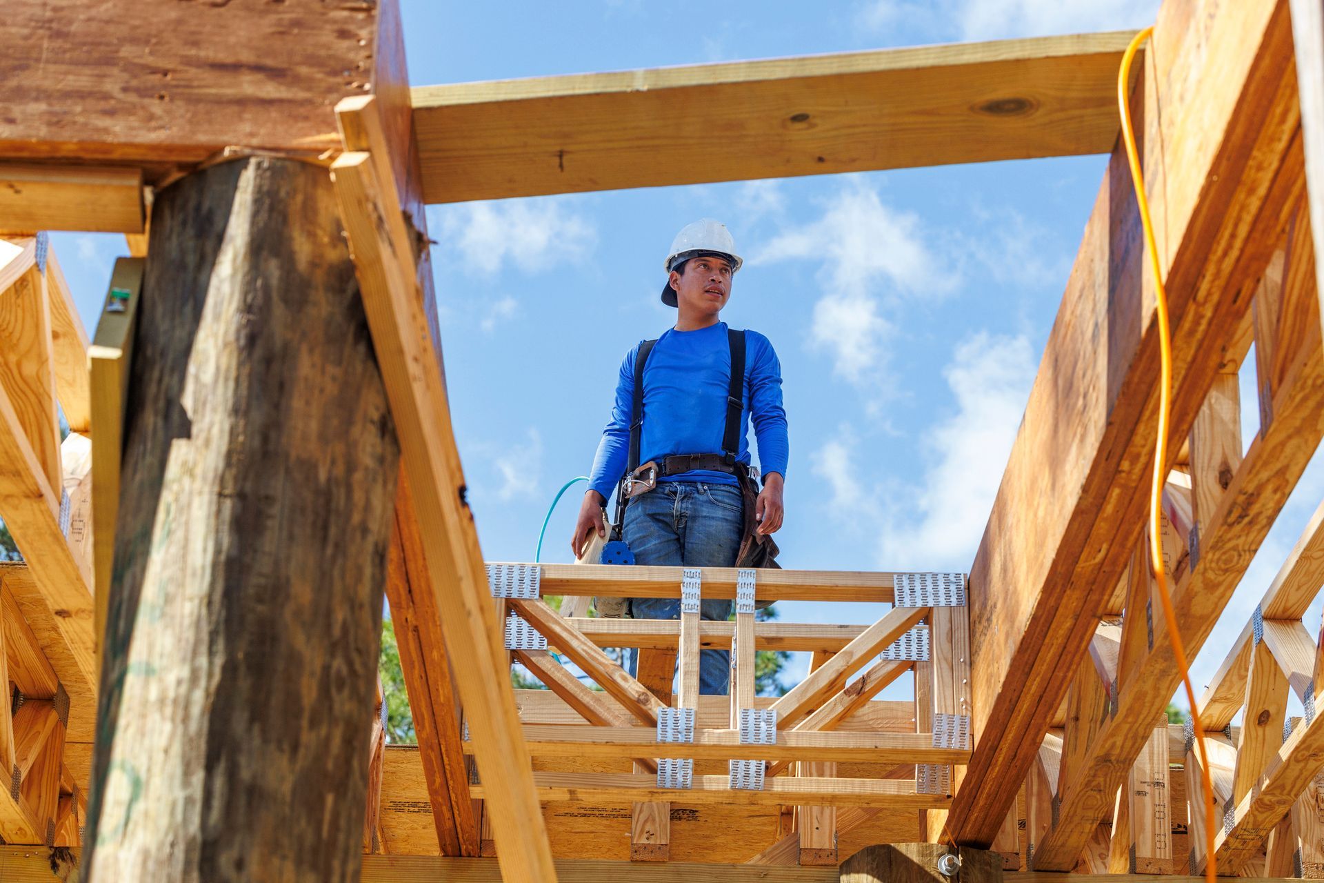 Worker standing on a wooden frame with posi trusses during building construction.