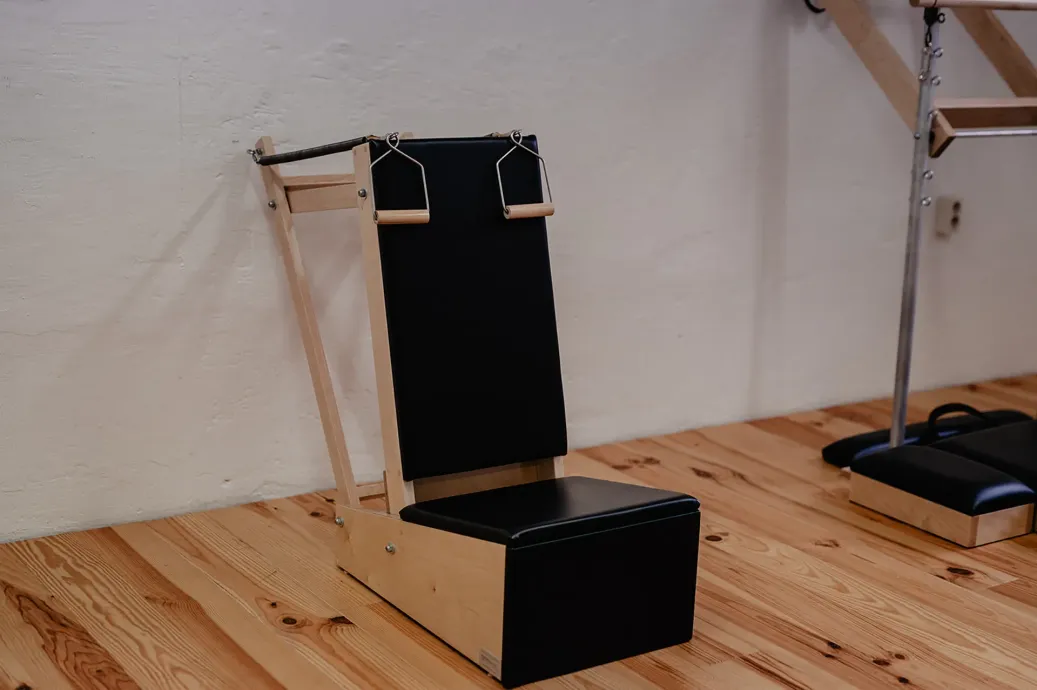 Archival Arm Chair: Holzstuhl mit schwarzer Sitzfläche und Rückenlehne auf einem hellen Holzboden in einem Innenraum