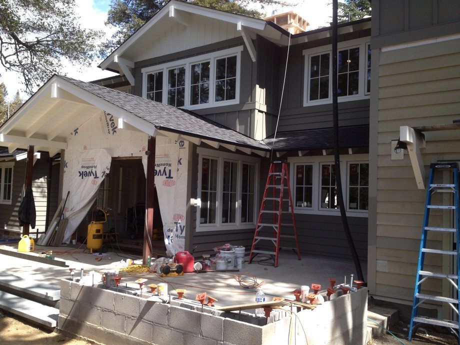 House exterior under renovation with ladders, tools, and construction materials on the front porch