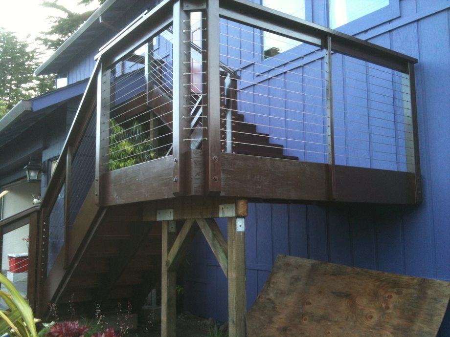 Exterior staircase and elevated deck with cable railing on a blue house