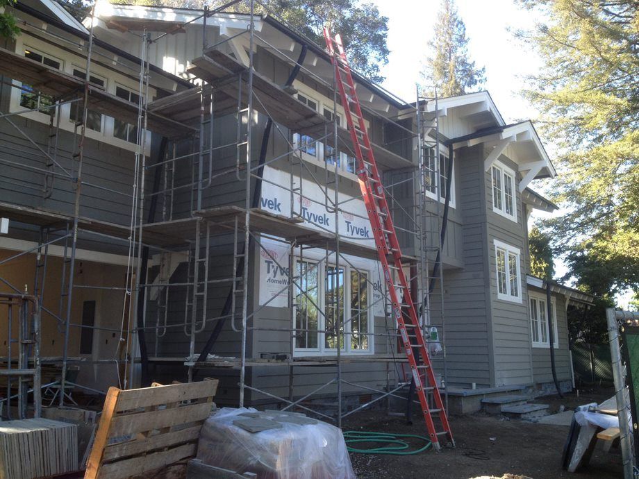 House under construction with scaffolding and a red ladder leaning against the front wall.