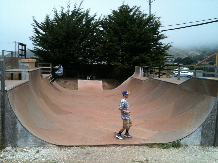 Skateboarder on a large concrete half-pipe at an outdoor skate park