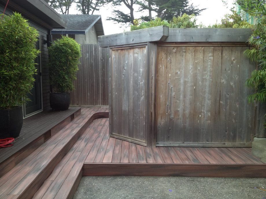 Wooden deck and hot tub in a backyard with trees and a fence