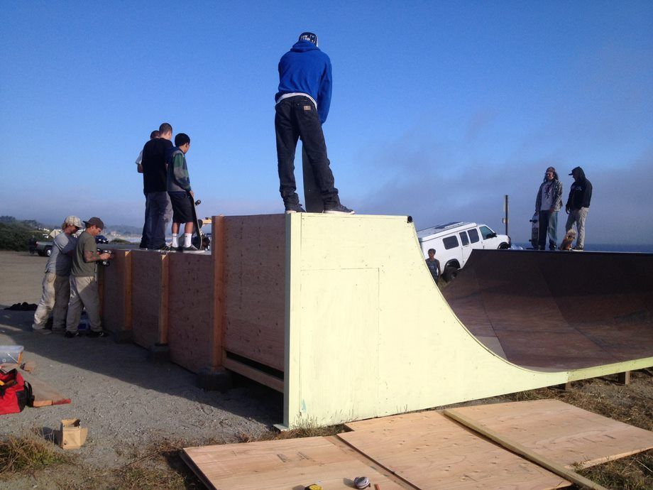 People standing on a skateboard ramp obstacle outdoors on a sunny day