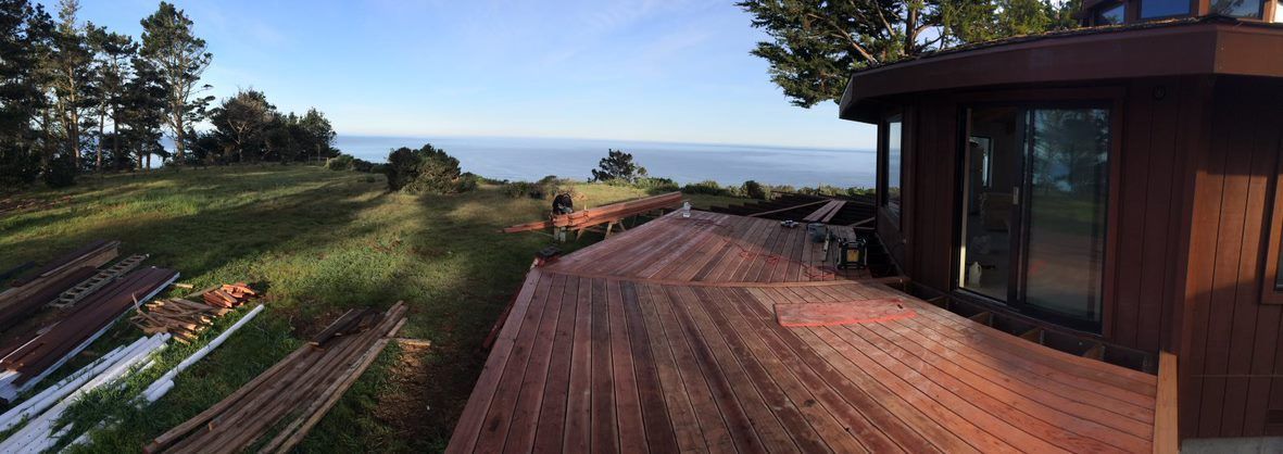 Garden path and wooden deck overlooking a coastal landscape at sunset