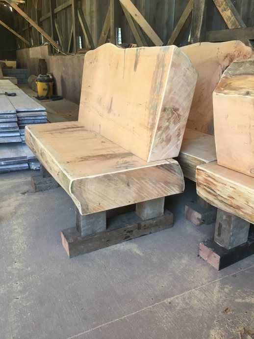 Wooden benches with backrests on blocks in a workshop or warehouse, unfinished and rustic.