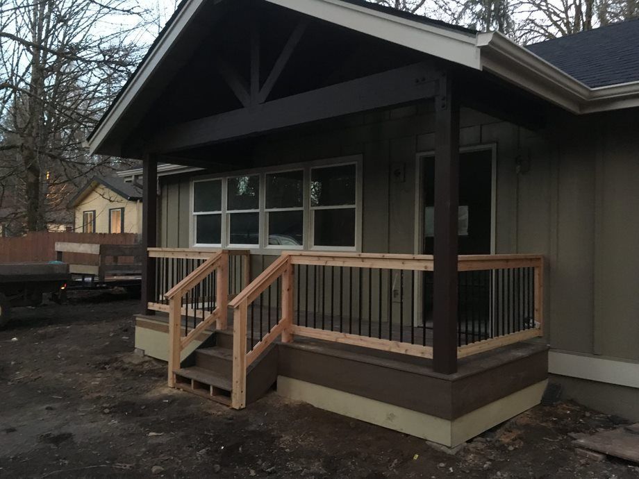Small house porch with wooden ramp and railings at a construction site