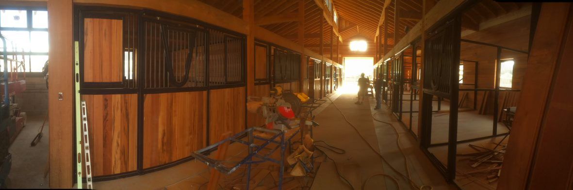 Covered corridor with bicycles and wooden doors, lit by warm lights at dusk.