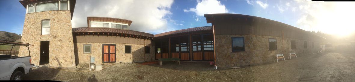 Panoramic view of a stone courtyard building with arched windows under a partly cloudy sky
