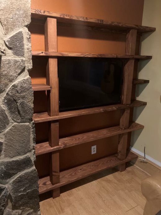 Wooden entertainment center built into a stone fireplace wall in a living room
