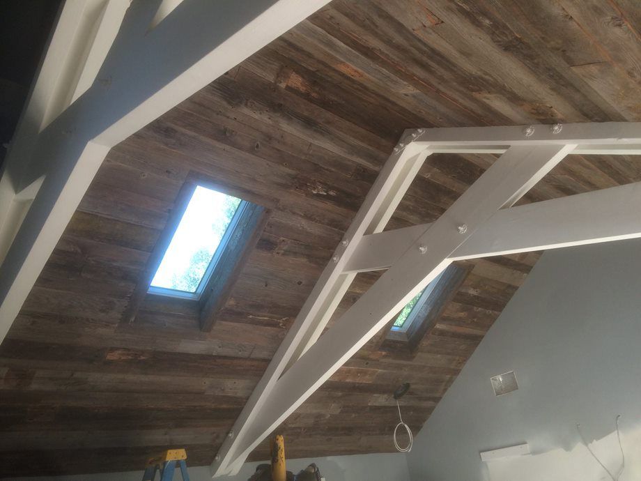 Wooden ceiling with skylights and white exposed beams in a room under construction