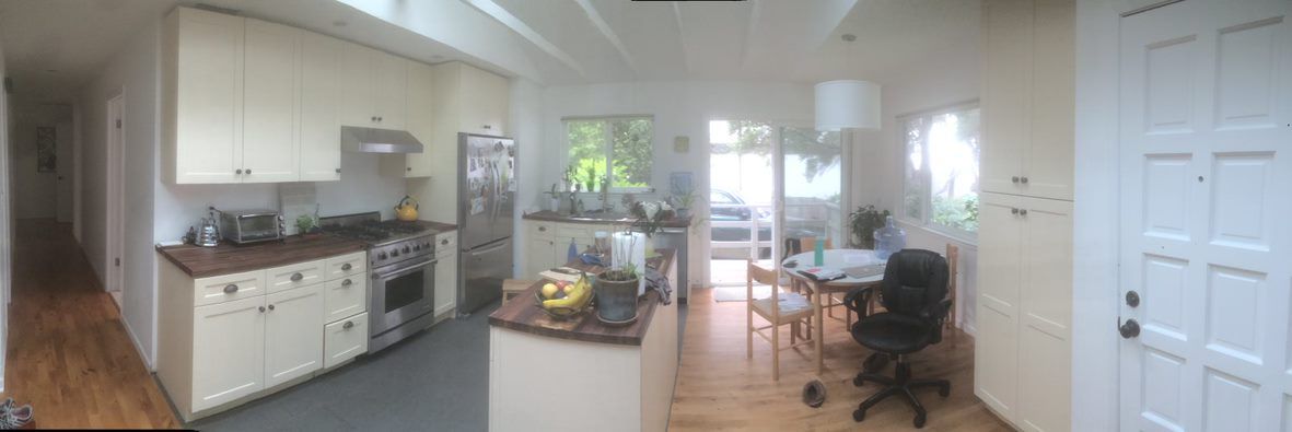 Bright open kitchen and dining area with white cabinets, wooden floors, and a round table by windows