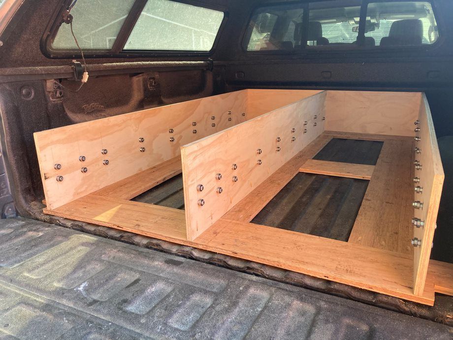 Wooden storage frame built in a pickup truck bed with side panels and compartments