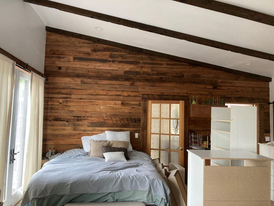 Cozy bedroom with wood-paneled wall, slanted ceiling, bed, and white dresser by a window