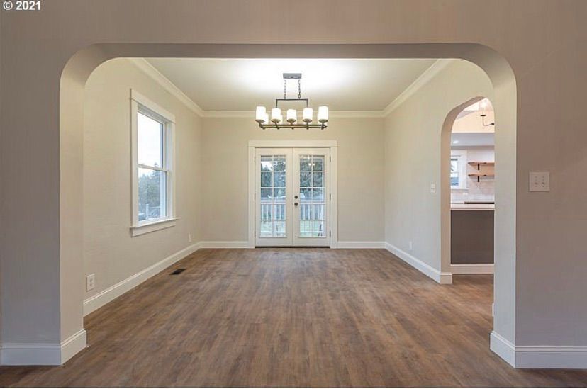 Empty dining room with wood floors, beige walls, chandelier, and French doors leading outside