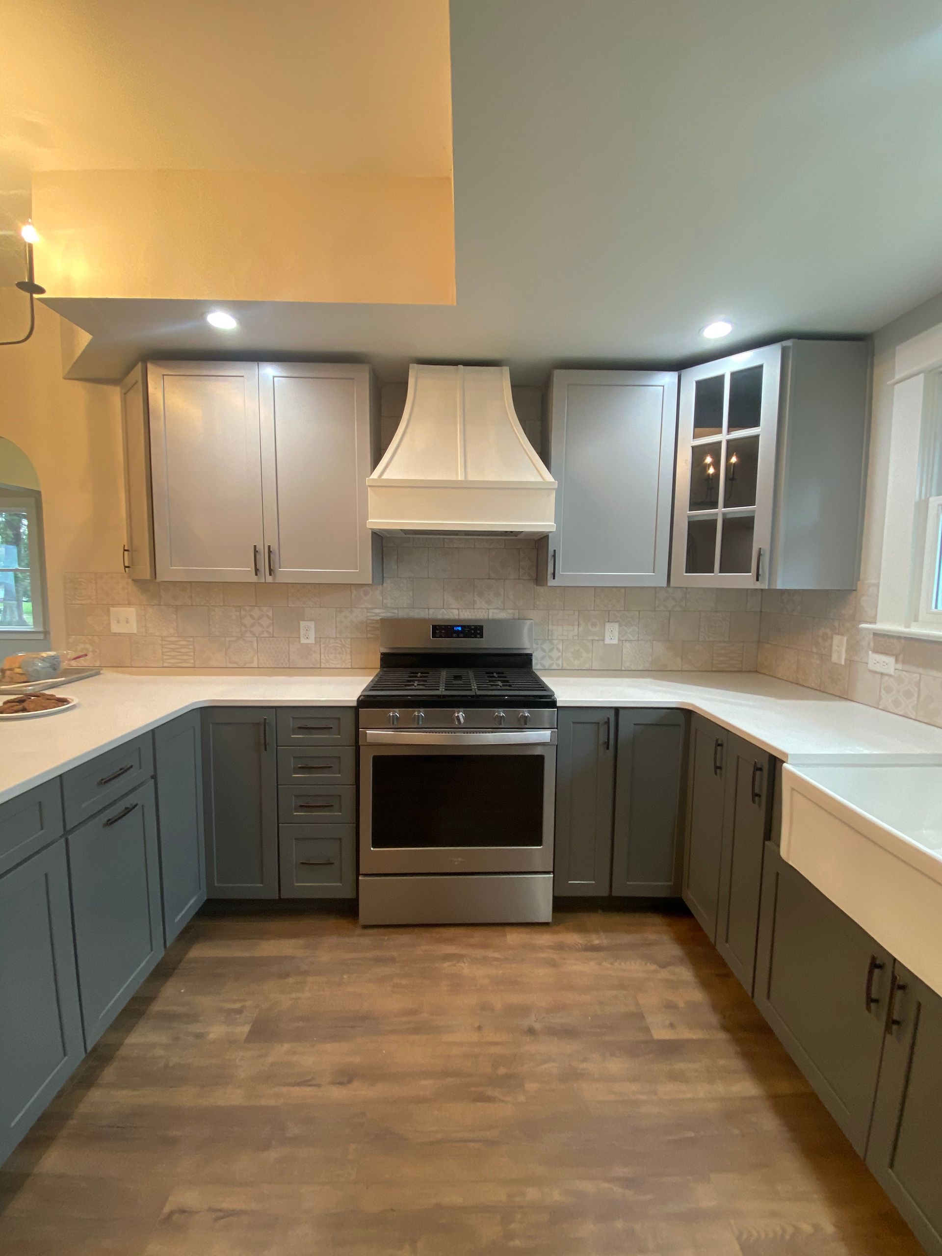 Modern kitchen with gray cabinets, white countertops, stainless stove, and wood flooring