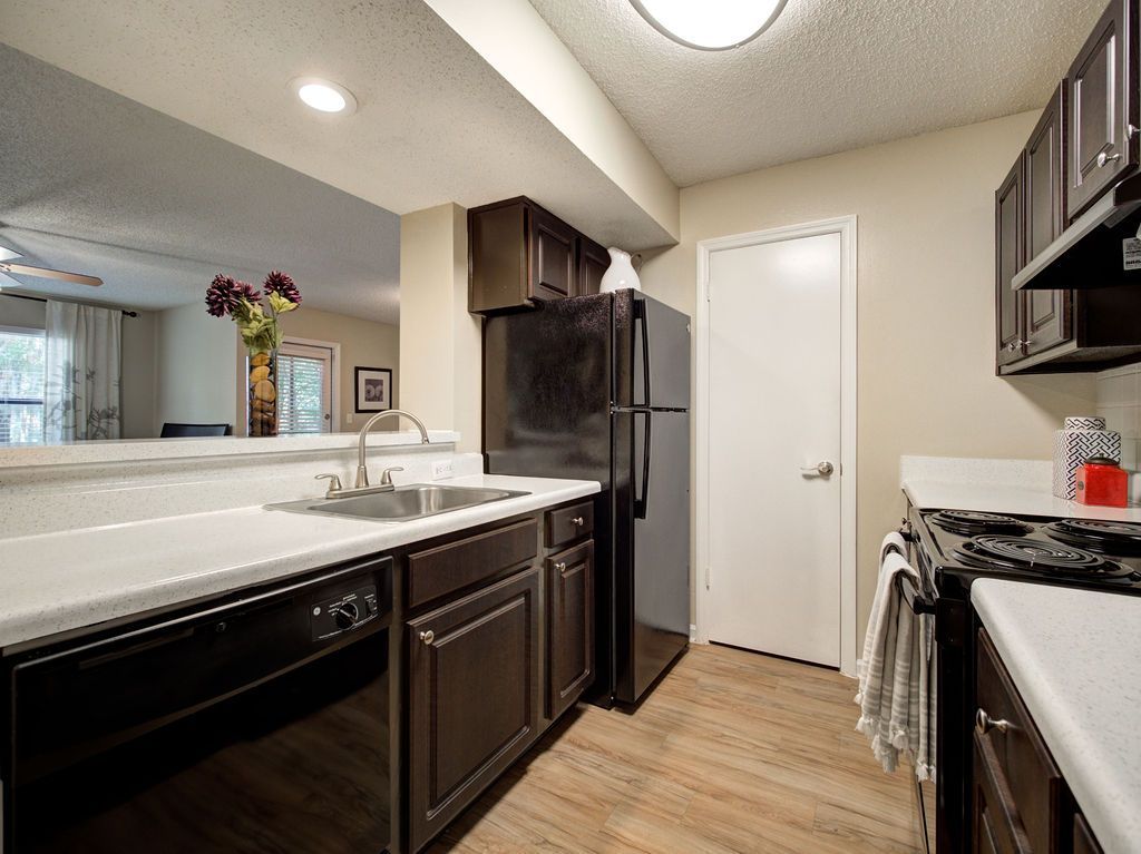 Modern kitchen with dark cabinets, white countertops, stainless appliances, and wood flooring at Grande Oasis at Carrollwood in Tampa, Florida.