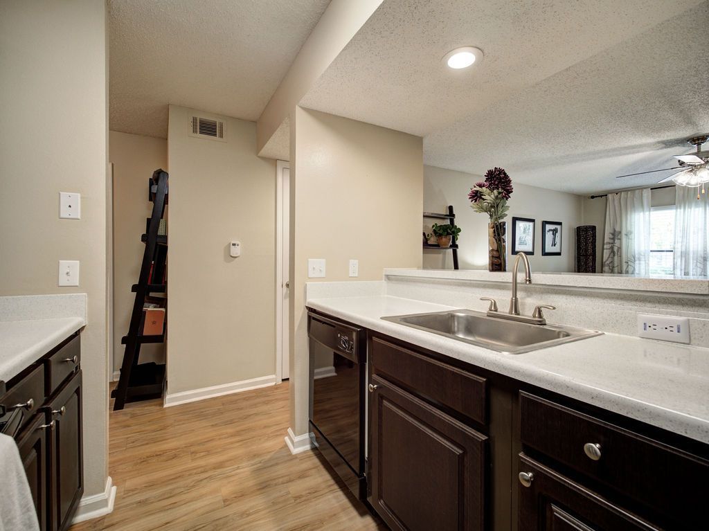 Kitchen island and sink overlooking a bright living area with wood floors and dark cabinets at Grande Oasis at Carrollwood in Tampa, Florida.