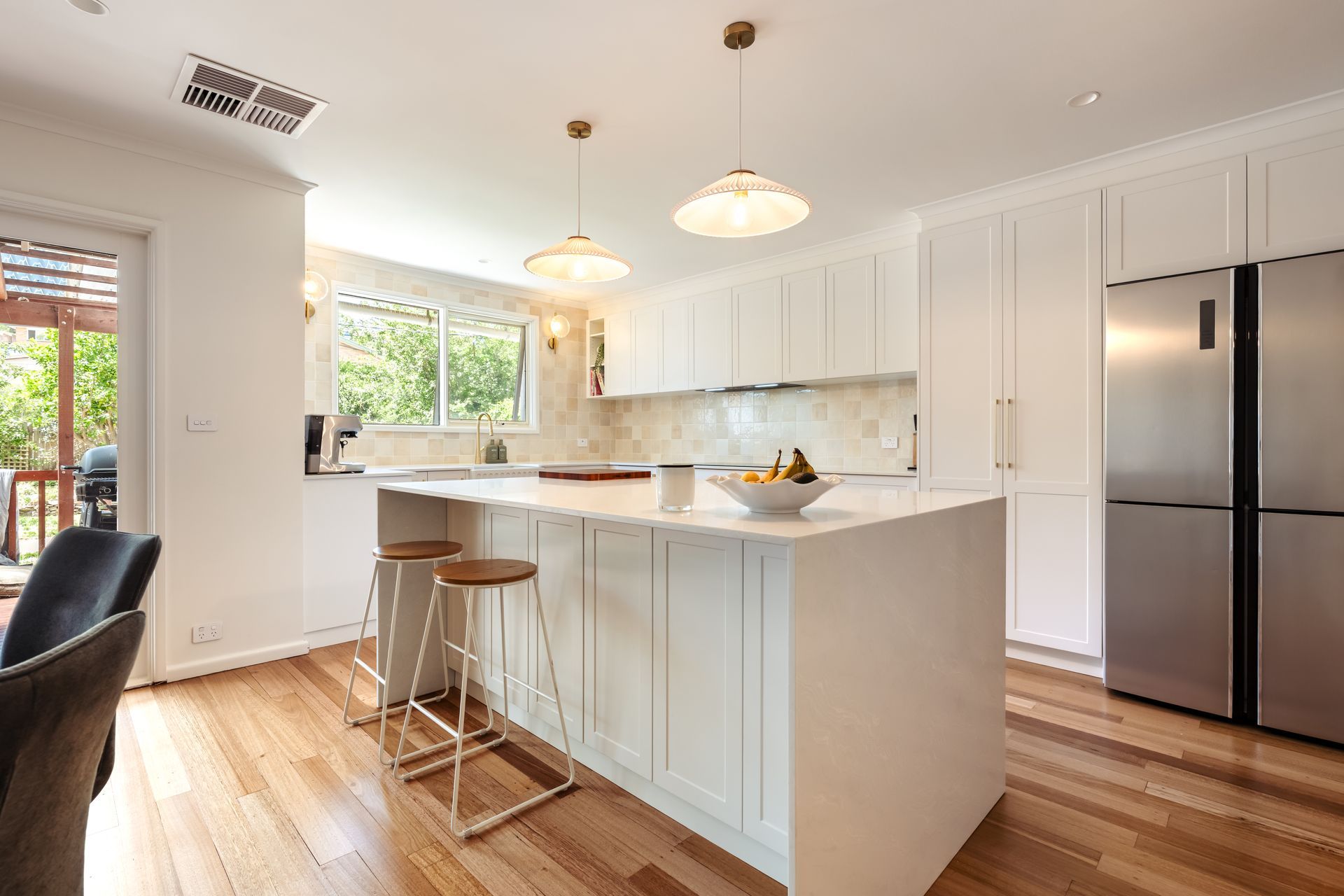 A kitchen with a large island and stools and a black refrigerator.