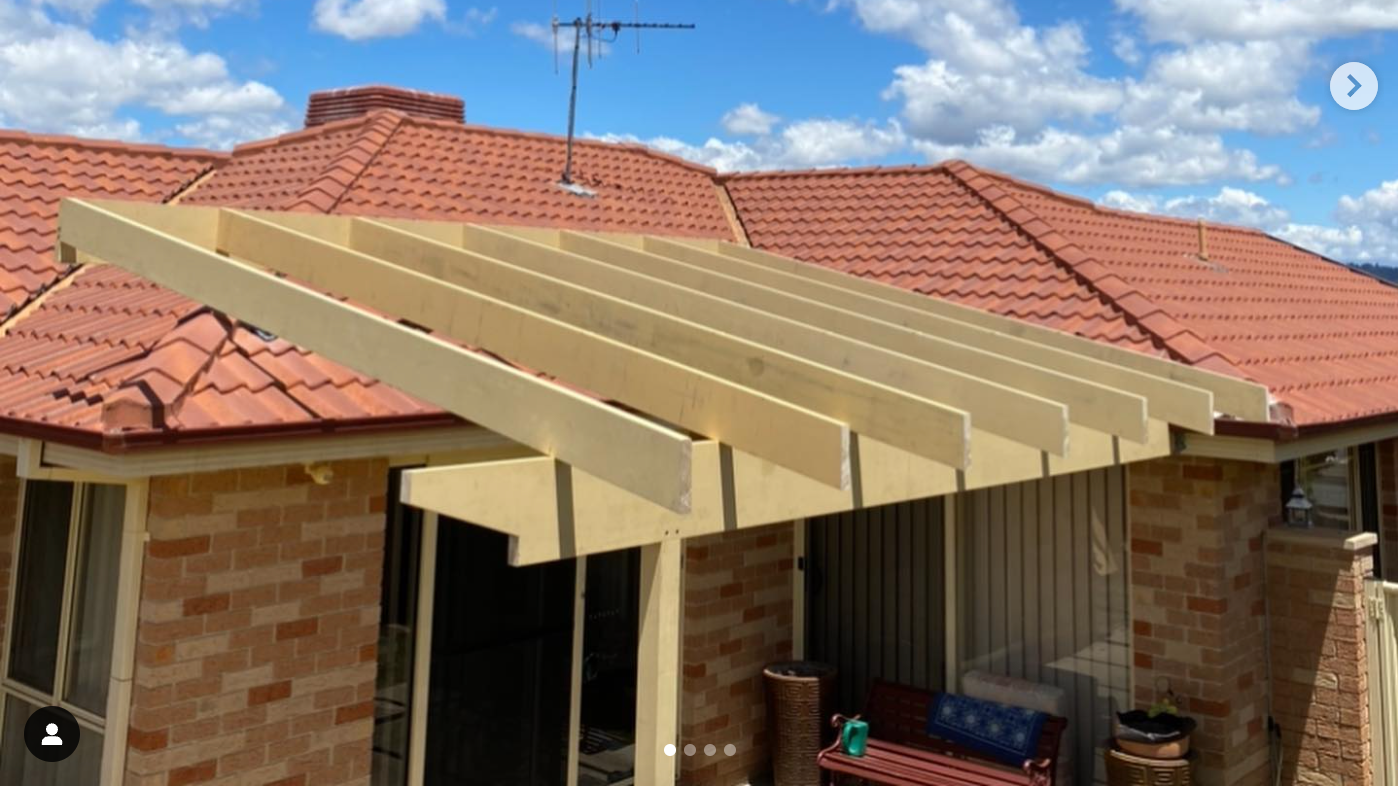 A brick house with a wooden pergola on the roof.