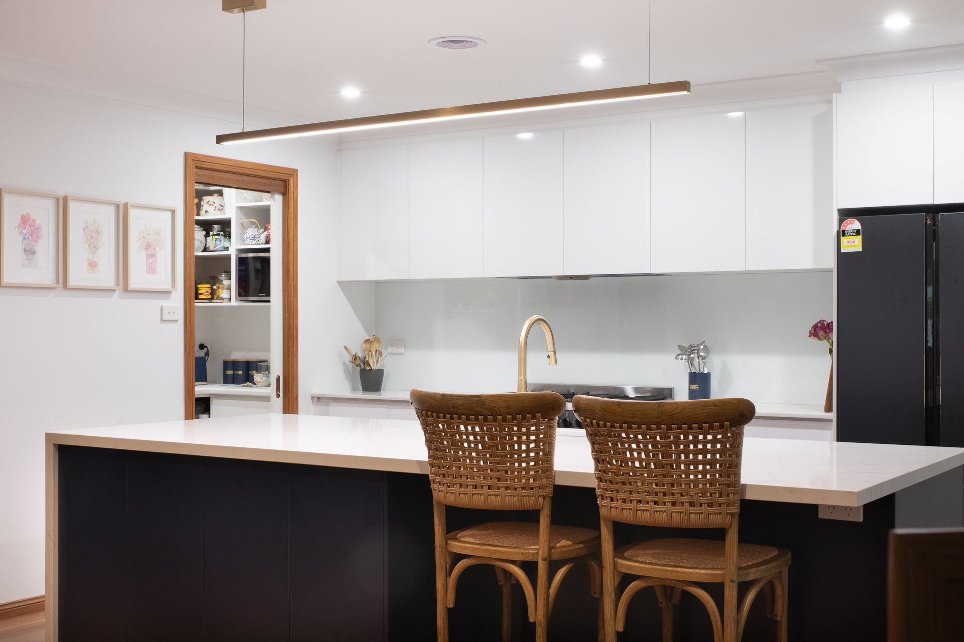 A kitchen with a large island and two wicker chairs.