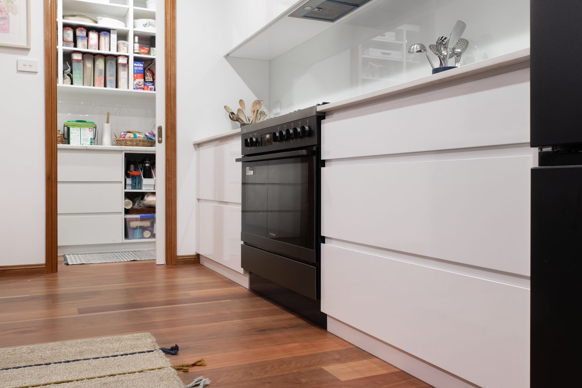 A kitchen with white cabinets and a black stove top oven.