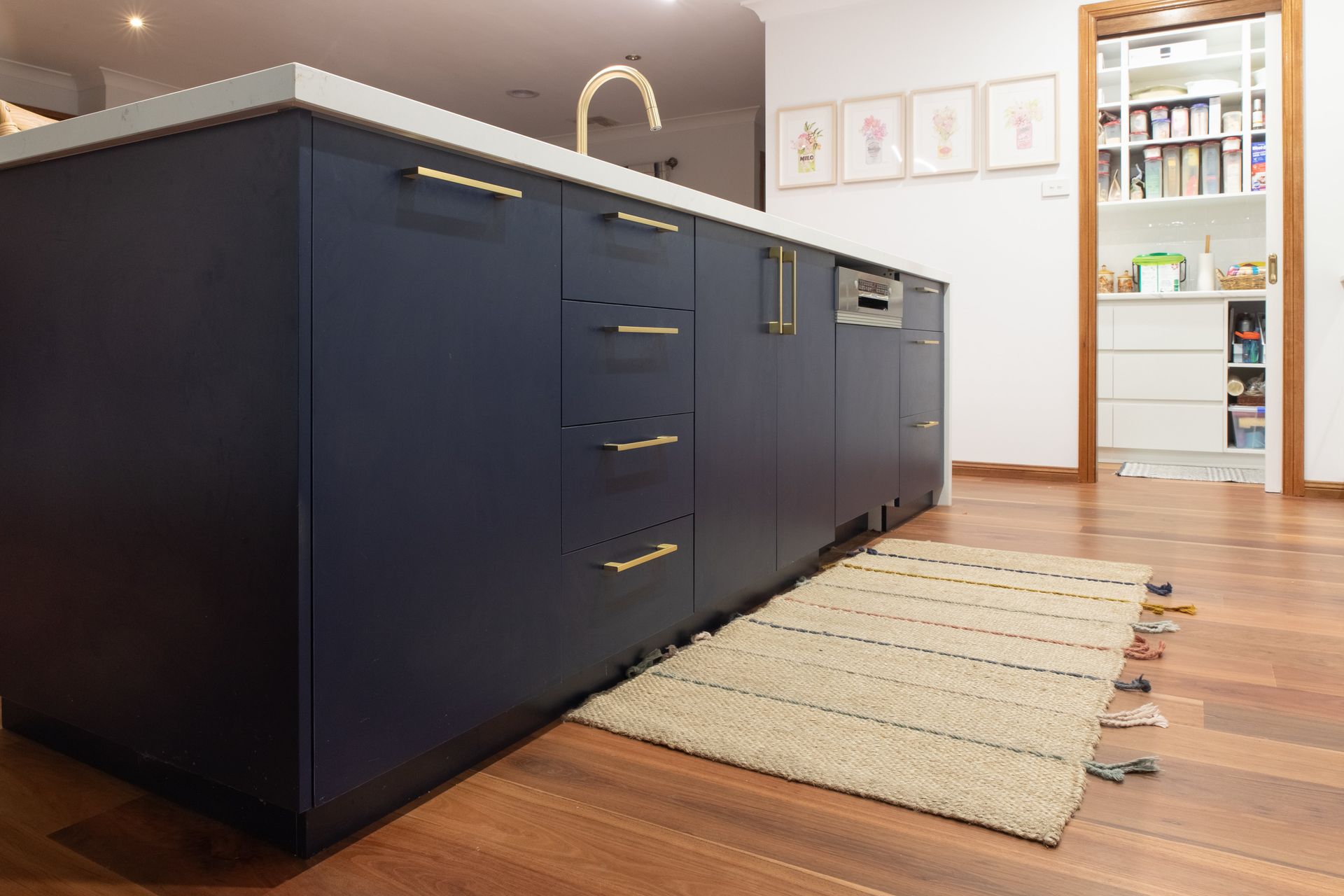 A kitchen with blue cabinets and a rug on the floor.