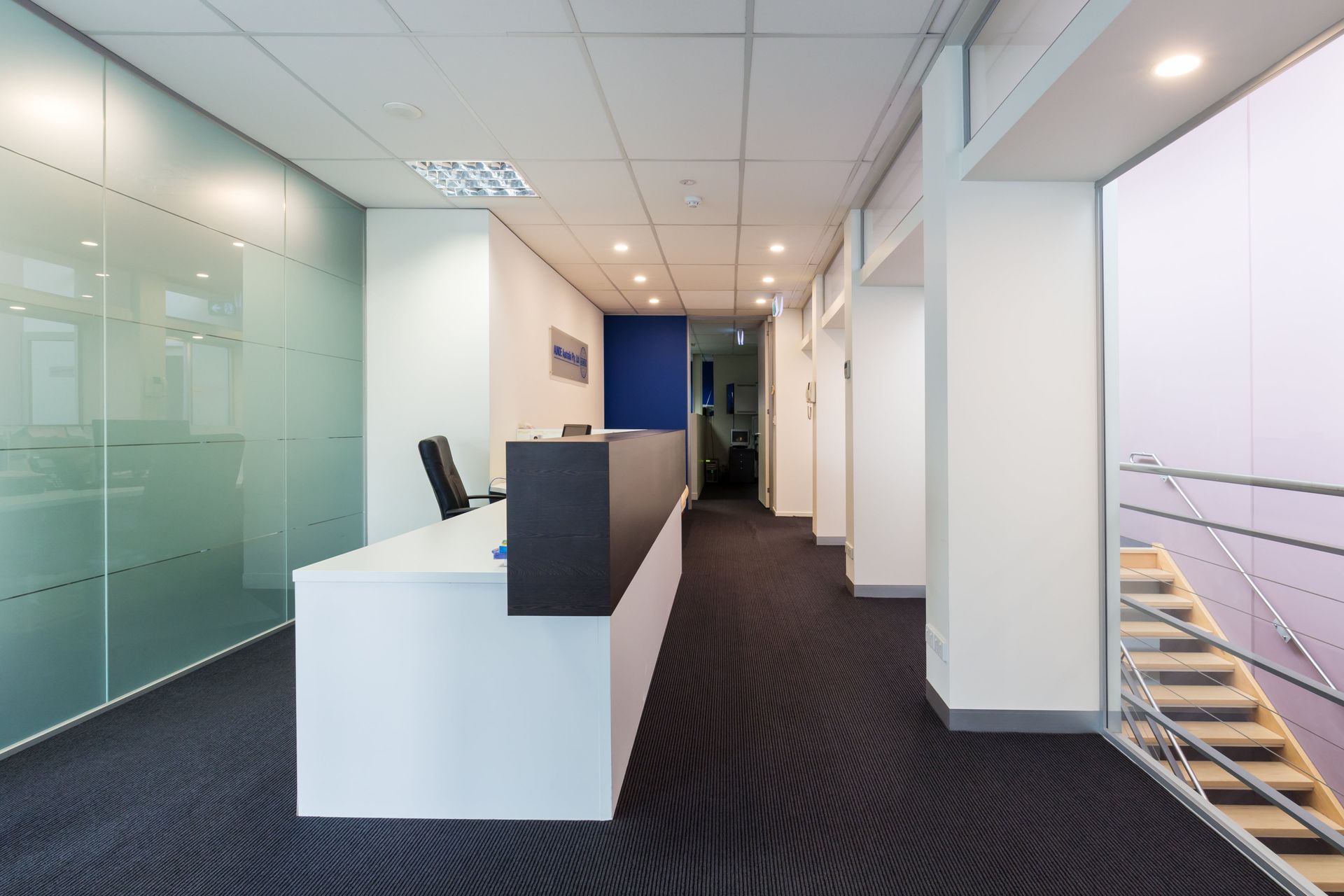 A long hallway with a reception desk and stairs