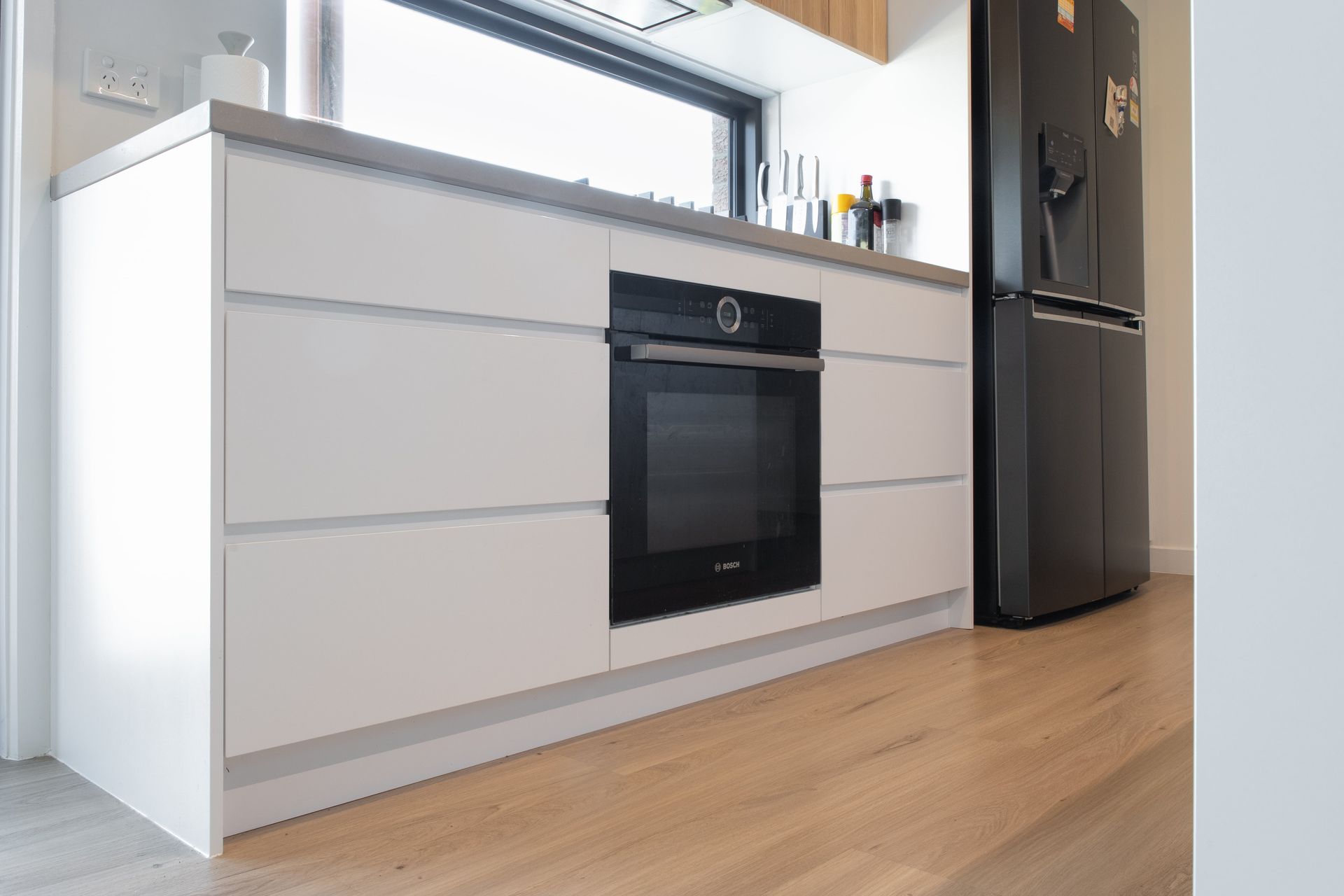 A kitchen with white cabinets and a black refrigerator.