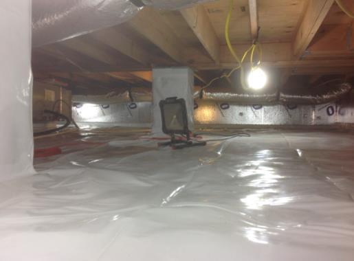 A light is sitting on the floor of a basement.